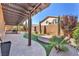 Landscaped backyard with a lush lawn, pavers, and a pergola-covered outdoor kitchen at 261 Via Morelli, Henderson, NV 89011