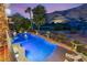 A luxurious backyard featuring a lagoon style pool with waterfall, mature landscaping, and mountain views at 2793 Red Arrow Dr, Las Vegas, NV 89135