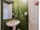 Bathroom featuring a pedestal sink with green walls, a decorative mirror, and a white door at 3042 Soft Horizon Way, Las Vegas, NV 89135