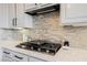 Close-up of the gas cooktop and range hood, complemented by stylish backsplash and countertops at 3042 Soft Horizon Way, Las Vegas, NV 89135