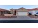 Single-story home with a two-car garage, desert landscaping, and a tile roof for a classic Southwest aesthetic at 390 Montego Ln, Boulder City, NV 89005