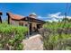 Rear exterior featuring covered patio, low shrubs, red tile roof, and brick-paved section at 3987 Saddlewood Ct, Las Vegas, NV 89121