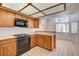 Functional kitchen featuring oak cabinets, black appliances, a tile countertop, and an open view to the dining space at 445 Intrepid Ct, Boulder City, NV 89005
