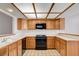 Well-lit kitchen featuring oak cabinets, a black range, tiled countertops, and a modern ceiling light fixture at 445 Intrepid Ct, Boulder City, NV 89005