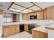 Bright kitchen with tiled countertops, oak cabinets, black appliances, and tiled flooring, well lit by a boxed ceiling light at 445 Intrepid Ct, Boulder City, NV 89005