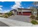 Two-car garage, lush shrubs, and greenery complement the stone driveway and modern exterior at 5264 Mystic Ivy Dr, Las Vegas, NV 89149