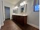 Bathroom with wood-look tile floor, double sink vanity, decorative mirrors, and a door to a private area at 5439 E Cansano St, Pahrump, NV 89061