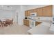Bright kitchen with white appliances, wood cabinets, and tile flooring, adjacent to a cozy dining area at 6138 Crystal Flower Way, North Las Vegas, NV 89031