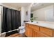 Well-lit bathroom featuring wood-look floors, a light wood vanity and a black shower curtain at 7288 Quarterhorse Ln, Las Vegas, NV 89148