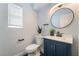 Stylish half bath with modern vanity, round mirror, and sleek fixtures at 7288 Quarterhorse Ln, Las Vegas, NV 89148
