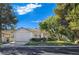 Charming single-story home featuring a lush green lawn, mature trees, and a two-car garage at 8981 Rivers Edge Dr, Las Vegas, NV 89117