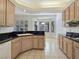 Bright kitchen with tile floors, light wood cabinets, black countertops, and a bay window with shutters at 8981 Rivers Edge Dr, Las Vegas, NV 89117