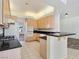 A kitchen featuring wood cabinets, black countertops and tile floors, connecting to a living area with wood floors at 8981 Rivers Edge Dr, Las Vegas, NV 89117