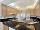 Spacious kitchen with wood cabinetry, black countertops, stainless steel appliances, and tile flooring at 8981 Rivers Edge Dr, Las Vegas, NV 89117