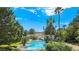 Community pool surrounded by lush landscaping, palm trees, and a charming clubhouse at 8981 Rivers Edge Dr, Las Vegas, NV 89117