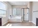 Sunlit bathroom features a soaking tub and a glass-enclosed shower with black trim, complemented by wood-look flooring at 10184 Juniper Valley St, Las Vegas, NV 89166