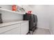 Bright laundry room features gray washer and dryer, white cabinets, quartz countertop, and shelf for storage at 12332 Switchgrass Ave, Las Vegas, NV 89138