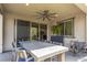 Covered patio with ceiling fan, large windows, dining table with seating and view to backyard at 12332 Switchgrass Ave, Las Vegas, NV 89138
