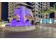 Nighttime view of the condo building entrance, featuring a water feature with purple lights and manicured landscaping at 2700 Las Vegas Blvd # 1804, Las Vegas, NV 89109