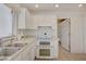 Bright kitchen features all-white cabinetry, countertops, tile flooring and stainless steel appliances with views to another room at 2808 Crown Ridge Dr, Las Vegas, NV 89134