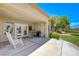 Covered patio featuring a rocking chair, table and chairs, and lush backyard views at 2808 Crown Ridge Dr, Las Vegas, NV 89134