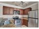 Galley kitchen featuring stainless steel appliances, granite countertops, and wood cabinets at 4050 Pacific Harbors Dr # 224, Las Vegas, NV 89121