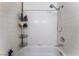 Shower/tub combination with white tile, showerhead, handheld sprayer, and built in corner shelving at 4335 Twin Peaks Dr, North Las Vegas, NV 89032