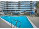 Upscale condo featuring a shimmering blue swimming pool with lounge chairs and a modern glass building in the background at 4525 Dean Martin Dr # 2903, Las Vegas, NV 89103