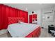 Bright bedroom features red tufted bed frame, red curtains, wood-look floors, and modern furnishings at 5375 Chestnut St, Las Vegas, NV 89119