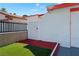 Side yard with white-painted brick wall, artificial turf, and a black wrought iron fence at 5375 Chestnut St, Las Vegas, NV 89119