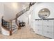 Inviting foyer with curved staircase, decorative iron railing, tile flooring, and a storage unit with decorative mirror at 6351 Abacus Farms Ct, Las Vegas, NV 89131