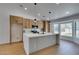 Bright kitchen with an island with waterfall countertop, wood cabinets, stainless appliances, and a window overlooking backyard at 7133 Tropical Island Cir, Las Vegas, NV 89129