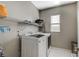 Functional laundry room with a washer, dryer, shelving, and a small window at 8531 W Oquendo Rd, Las Vegas, NV 89113