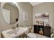Stylish powder room with a pedestal sink, decorative mirror, and modern decor at 8531 W Oquendo Rd, Las Vegas, NV 89113