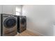 Well-lit laundry room features modern stainless steel washer and dryer units and wood-style flooring at 9319 White Waterfall Ave, Las Vegas, NV 89149