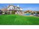 An expansive backyard with lush green grass, manicured landscaping, and a charming two-story white home at 9605 Verlaine Ct, Las Vegas, NV 89145
