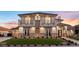 Elegant two-story home featuring dual balconies, stone accents, manicured lawn, and arched entryway at 9605 Verlaine Ct, Las Vegas, NV 89145