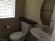 Cozy half-bathroom featuring a pedestal sink and window at 3175 Obscured Light Walk, Henderson, NV 89044