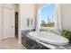Bright bathroom featuring a marble-topped tub and a large window with decorative curtains at 4317 Velvet Ridge Ct, Las Vegas, NV 89129