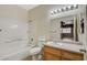 Bathroom with tiled tub, wood vanity and mirror with view into the bedroom with ceiling fan at 4730 E Craig Rd # 1005, Las Vegas, NV 89115