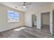 A light-filled bedroom with gray wood floors, a ceiling fan, and ensuite bathroom access at 4801 Stoneham, Pahrump, NV 89061