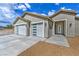Close-up of home featuring a three-car garage, desert landscaping, and stylish exterior lighting at 4801 Stoneham, Pahrump, NV 89061