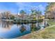 Scenic view of a home overlooking a serene pond surrounded by lush greenery and mature trees at 5058 Crooked Stick Way, Las Vegas, NV 89113