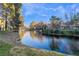 Scenic view of a home overlooking a serene pond surrounded by lush greenery and mature trees at 5058 Crooked Stick Way, Las Vegas, NV 89113