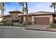 Charming home featuring a stone turret, lush landscaping, and a paved driveway leading to a two-car garage at 51 Avenida Sorrento, Henderson, NV 89011