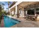 Expansive covered patio with an outdoor dining area overlooking a luxurious pool with beautiful travertine pavers at 51 Avenida Sorrento, Henderson, NV 89011