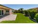 Lovely backyard featuring green lawn, brick patio, privacy landscaping, and a ceiling fan at 6085 Ryan Ranch Ave, Las Vegas, NV 89130