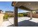 Backyard view features a covered patio, a concrete area, and block wall fencing with planted shrubs at 6442 Kobe Knoll Ct, Las Vegas, NV 89141