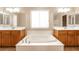Bright bathroom featuring double sinks, a large soaking tub, and a window for natural light at 6591 Gertrude Ct, Las Vegas, NV 89141