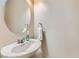 Elegant half bathroom featuring a circular mirror, modern fixtures, and a pristine white sink at 8295 Nebula Cloud Ave, Las Vegas, NV 89131